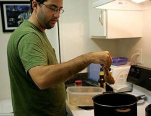 Justin holding a chicken leg above a cooking pot