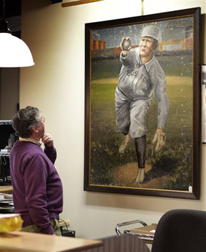 In this photo made Tuesday, March 11, 2014, auctioneer Floyd Hartford examines a 1910 painting of Cy Young in a Boston Red Sox uniform at the Saco River Auction House in Biddeford, Maine.
