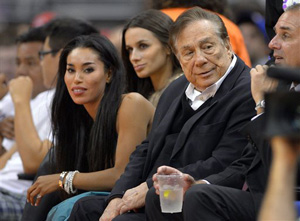 In this photo taken on Friday, Oct. 25, 2013, Los Angeles Clippers owner Donald Sterling, right, and V. Stiviano, left, watch the Clippers play the Sacramento Kings. NBA spokesman Mike Bass said in a statement Saturday, April 26, 2014, that the league is in the process of authenticating the validity of the recording posted on TMZ's website. Bass called the comments &quot;disturbing and offensive.&quot;