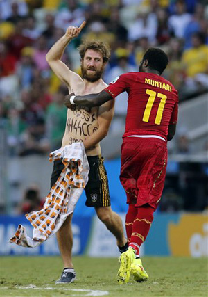 Ghana's Sulley Muntari assists the Neo-Nazi sympathizer off the pitch after he ran on during the group G World Cup soccer match between Germany and Ghana at the Arena Castelao in Fortaleza, Brazil, Saturday, June 21, 2014.