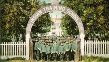 group photo of students at the gate of an American Indian boarding school