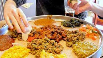 people sample Ethiopian dishes arranged on a platter