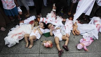 Two babies are placed between dolls covered with red paint during a demonstration, most of them women and children, against Israel's military offensive in Gaza, Tuesday, July 22, 2014, in Berlin, Germany. Several hundred pro-Palestinian protesters demanded a halt to military action in Gaza.