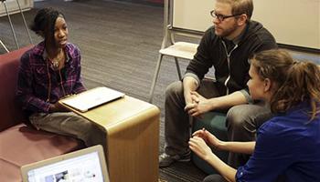 English teacher Tom Rademacher talks with his high school juniors Kierra Murray, left, and Ana Silverman, right, Tuesday, Dec. 2, 2014, at Fair School in Minneapolis. Knowing that the grand jury decision not to indict a white officer who shot and killed a black teen in Ferguson, Mo., would be on the minds of his students, Rademacher put aside his lesson plans and asked them a question: How did they feel?