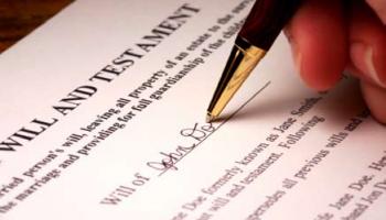 a hand signing a Will document