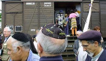 This Aug. 20, 2001, file photo shows French Holocaust survivors gathering at the site of the former Drancy detention camp, north of Paris, France. From Aug. 20, 1941 until the end of World War II, more than 70,000 Jewish men, women and children passed through Drancy on their way to Nazi extermination camps, particularly Auschwitz. The wagon is part of the memorial site.