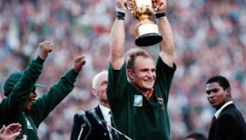 In this June 24, 1995, file photo, South African rugby captain Francios Pienaar, center, raises the trophy after receiving it from South African President Nelson Mandela, left, who wears a South African rugby shirt, after they defeated New Zealand in the final 15-12 at Ellis Park, Johannesburg. Mandela strode onto the field wearing South African colors and bringing the overwhelmingly white crowd of more than 60,000 to its feet.