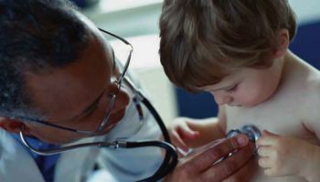 doctor checking heartbeat of child with stethoscope