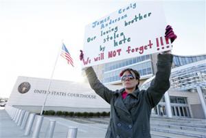 Amelie Hahn, braves cold weather as she holds a poster memorializing the 2011 rundown death of James Craig Anderson in front of the federal courthouse in Jackson, Miss., Wednesday, Jan. 7, 2015. Two of the men charged in the series of 2011 racial beatings that resulted in Anderson's death attended change-of-plea hearing.