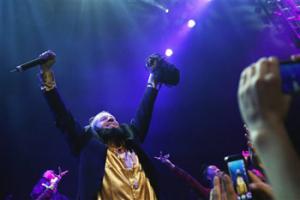 In this photo taken May 16, 2014, Macklemore of the group Macklemore & Ryan Lewis strikes a pose as he performs "Thrift Shop" to a mob of waving fans during Vivid: Spectacle Opening Night Party at the EMP Museum in Seattle.