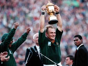 In this June 24, 1995, file photo, South African rugby captain Francios Pienaar, center, raises the trophy after receiving it from South African President Nelson Mandela, left, who wears a South African rugby shirt, after they defeated New Zealand in the final 15-12 at Ellis Park, Johannesburg. Mandela strode onto the field wearing South African colors and bringing the overwhelmingly white crowd of more than 60,000 to its feet.