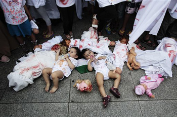 Two babies are placed between dolls covered with red paint during a demonstration, most of them women and children, against Israel's military offensive in Gaza, Tuesday, July 22, 2014, in Berlin, Germany. Several hundred pro-Palestinian protesters demanded a halt to military action in Gaza.