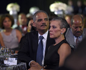 Attorney General Eric Holder, center, sits with his wife Sharon Malone, right, as they wait for President Barack Obama to speak at the Congressional Black Caucus Foundation's 44th Annual Legislative Conference Phoenix Awards Dinner in Washington, Saturday, Sept. 27, 2014.