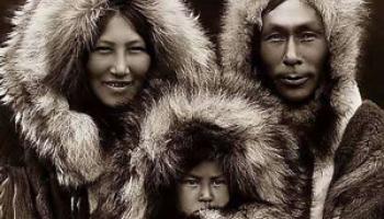Eskimo man, woman and child wearing winter parkas.