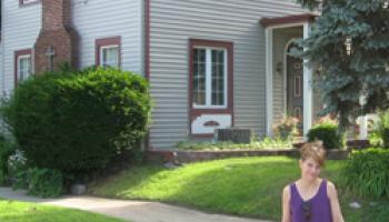 Christine Shunko standing in front of her home