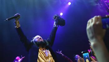 In this photo taken May 16, 2014, Macklemore of the group Macklemore & Ryan Lewis strikes a pose as he performs "Thrift Shop" to a mob of waving fans during Vivid: Spectacle Opening Night Party at the EMP Museum in Seattle.