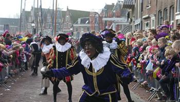 In this Nov. 16, 2013 file photo a "Zwarte Piet" or "Black Pete", jokes with children after arriving with Sinterklaas, or Saint Nicholas, by steamboat in Hoorn, north-western Netherlands. Amsterdam’s mayor and organizers of a large children’s winter festival have unveiled plans on Thursday, Aug. 14, 2014 to reform the image of “Black Pete” in order to remove perceived racist elements over a period of years.