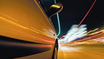 car driving city streets with lights streaking past