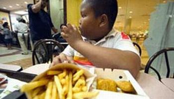 An obese African-American boy eating french fries and chicken strips