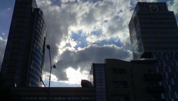 sunshine and clouds rising above buildings