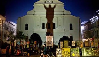 In this Friday, Feb. 1, 2013 file photo, a pedestrian walks her bicycle past a silhouette of Jesus Christ projected against the Cathedral-Basilica of Saint Louis King of France in New Orleans, two days ahead of the NFL Super Bowl football game between the San Francisco 49ers and the Baltimore Ravens. "I find it fascinating that that's what people really want to know -- what race was Jesus.