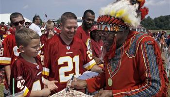 In this Saturday, Aug. 4, 2012 file photo, Zena "Chief Z" Williams, unofficial mascot of the Washington Redskins, signs autographs during fan appreciation day at the Redskins' NFL football training camp at Redskins Park in Ashburn, Va. The name Washington Redskins has inspired protests, hearings, editorials, lawsuits, letters from Congress, even a presidential nudge. Yet behind the headlines, it’s unclear how many Native Americans think “Redskins” is a racial slur.