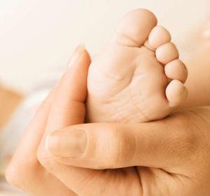 an adult hand holding a babies foot