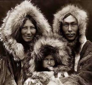 Eskimo man, woman and child wearing winter parkas.