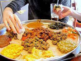 people sample Ethiopian dishes arranged on a platter