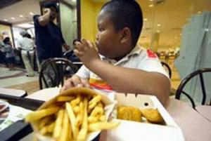 An obese African-American boy eating french fries and chicken strips