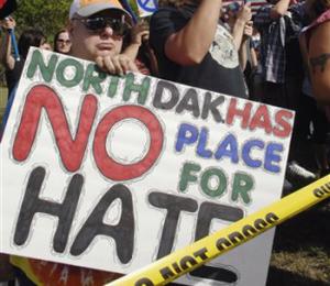 In this Sept. 22, 2013. file photo, Jay Schechter holds a sign, while participating in a protest rally outside Craig Cobb's house in Leith, N.D. The town of Leith has invited Gov. Jack Dalrymple and members of North Dakota's congressional delegation to help the community celebrate its birthday and the end of a months-long clash with Cobb, who unsuccessfully tried to take over the town. Leith is holding is 105th birthday bash the weekend of July 19-20.