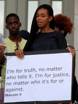 protester holding sign reading: "I'm for truth, no matter who tells it. I'm for justice, no matter who it's for or against." - Malcolm X